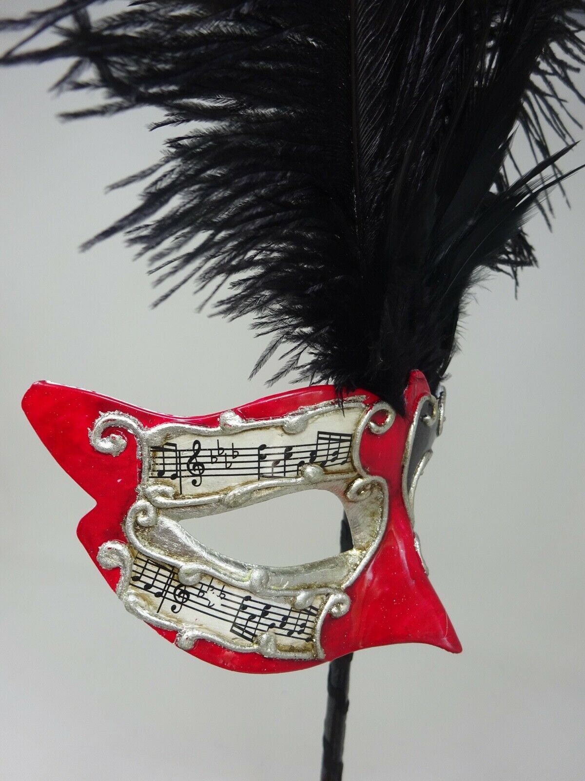 Ladies Red, Black and Silver Musical Masquerade Mask for Masked Ball with Layered Long Black Feathers Hand Held on a Wooden Stick